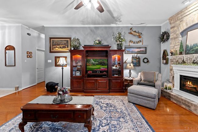 Living room with ornamental molding, ceiling fan, a fireplace, and light wood-type flooring | Image 10