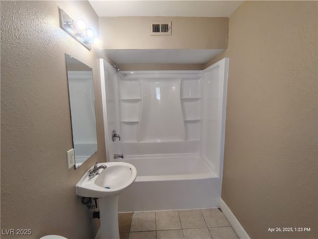 Bathroom with tile patterned floors, visible vents, a textured wall, and tub / shower combination | Image 10