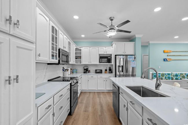 Kitchen featuring glass insert cabinets, a sink, ornamental molding, white cabinetry, and stainless steel appliances | Image 7