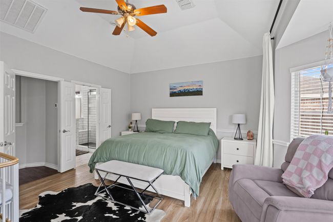 Downstairs primary bedroom with laminate floors, a ceiling fan, ensuite bath, and high vaulted ceiling | Image 20