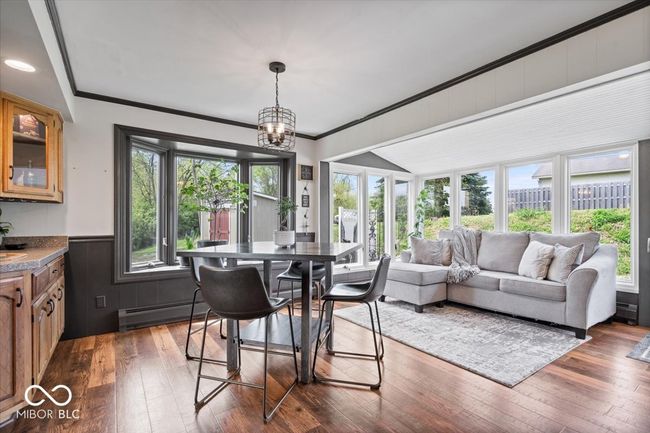 dining room with a baseboard heating unit, dark wood-style flooring, wainscoting, crown molding, and a chandelier | Image 7