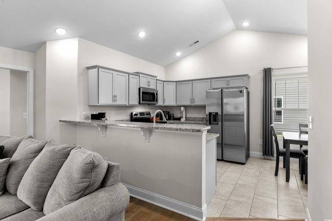 Kitchen with stainless steel appliances, gray cabinets, a peninsula, light stone countertops, and open floor plan | Image 12
