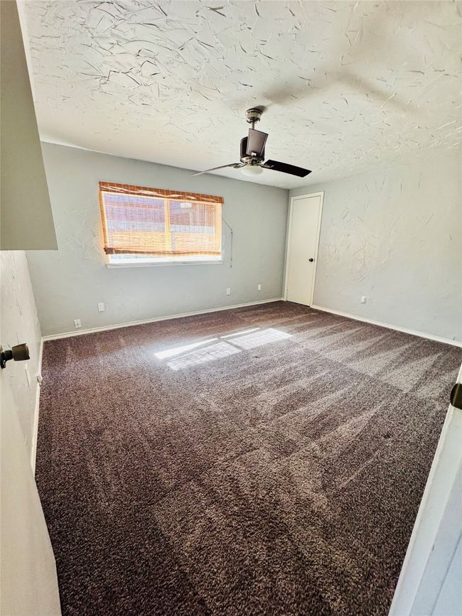 Spare room featuring ceiling fan, carpet, and a textured ceiling | Image 18