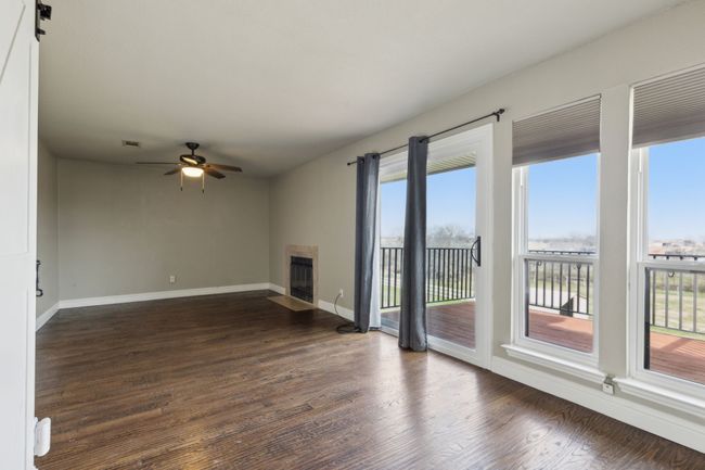 Unfurnished living room featuring a fireplace with flush hearth, dark wood-style flooring, and plenty of natural light | Image 18