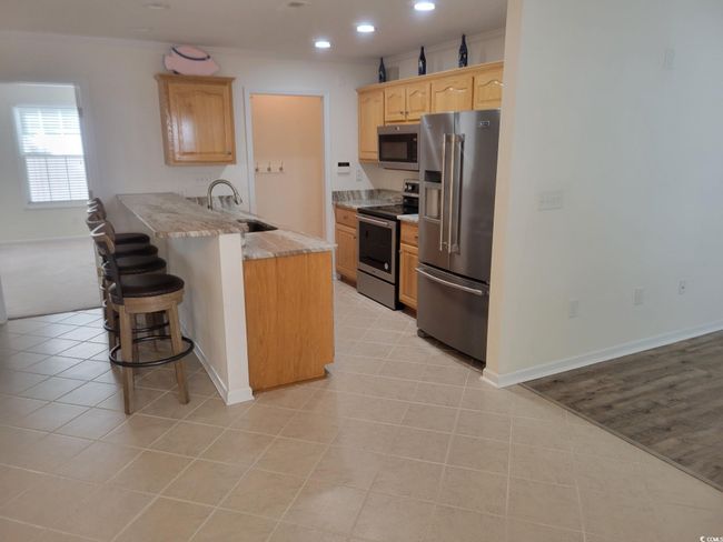 Kitchen featuring stainless steel appliances, a peninsula, a kitchen bar, light brown cabinets, and recessed lighting | Image 35