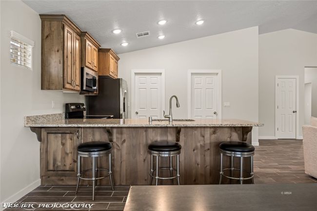 Kitchen with a sink, stainless steel appliances, lofted ceiling, wood tiled floors, and baseboards | Image 27
