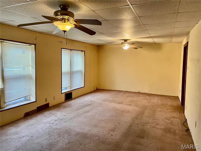 Carpeted empty room with a drop ceiling and ceiling fan | Image 5