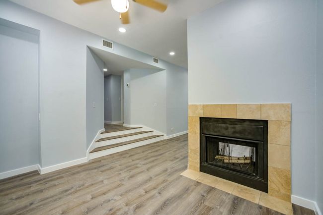 Unfurnished living room featuring a tiled fireplace, ceiling fan, wood finished floors, and recessed lighting | Image 9