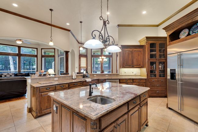 Kitchen with stainless steel appliances, a center island with sink, light tile patterned flooring, crown molding, and open floor plan | Image 14