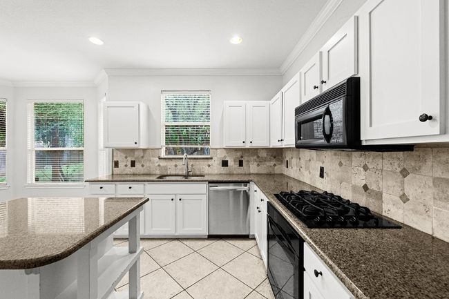 Kitchen featuring black appliances, ornamental molding, plenty of natural light, light tile patterned flooring, and white cabinets | Image 5