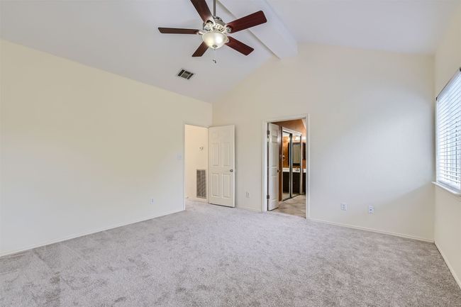 Unfurnished bedroom with beamed ceiling, light colored carpet, baseboards, high vaulted ceiling, and connected bathroom | Image 14