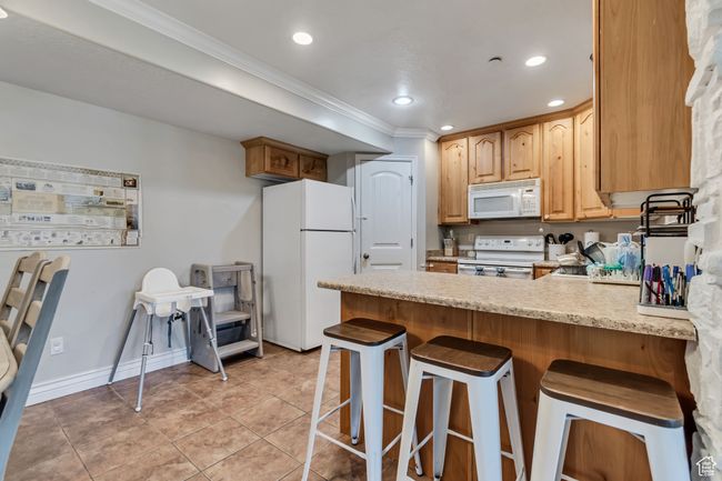 Kitchen with white appliances, a peninsula, and light tile patterned floors. | Image 11