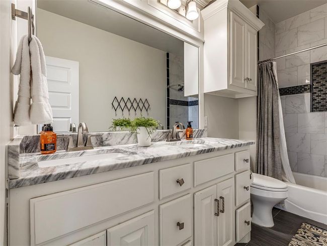 Full bathroom featuring double vanity, a sink, toilet, and shower / bathtub combination with curtain | Image 28