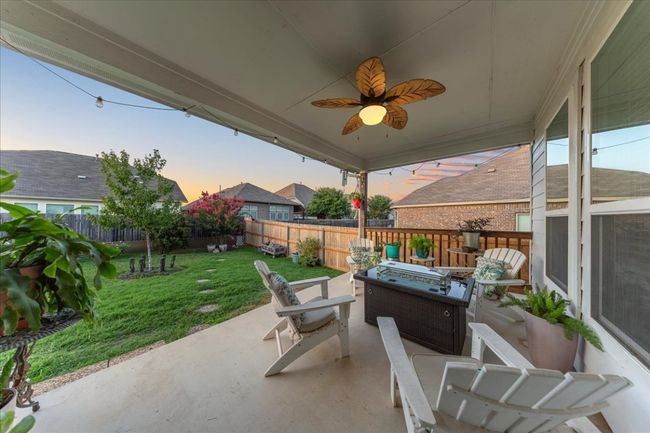 Patio terrace at dusk with a fire pit, a patio, a fenced backyard, and a ceiling fan | Image 15