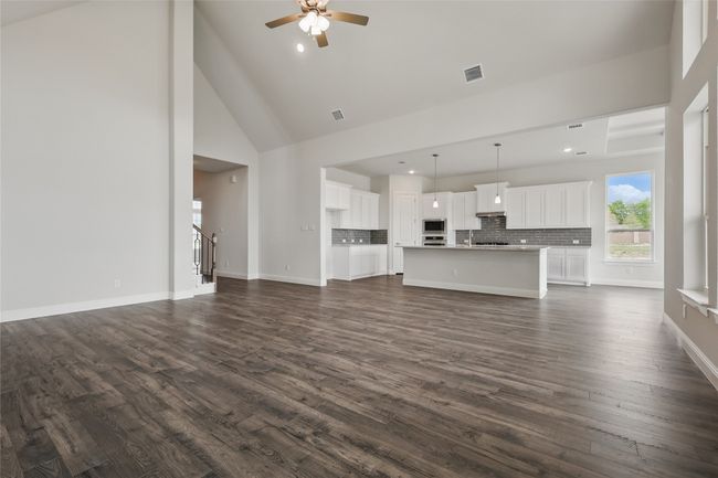 Unfurnished living room with a ceiling fan, visible vents, baseboards, and dark wood finished floors | Image 11