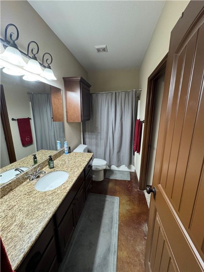 Full bathroom featuring vanity, finished concrete floors, and shower / bath combination with curtain | Image 21
