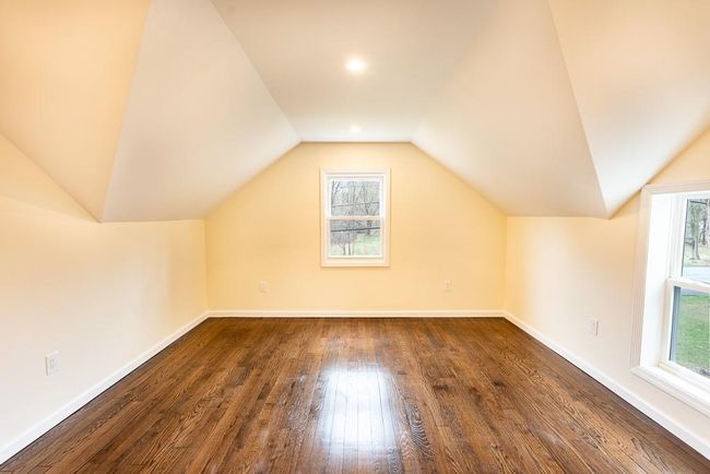 Master bedroom on second floor featuring dark wood finished floors, visible vents, baseboards, and lofted ceiling | Image 26