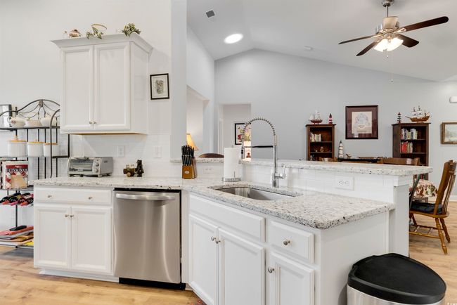 Kitchen with lofted ceiling, sink, dishwasher, light stone countertops, and white cabinets | Image 5