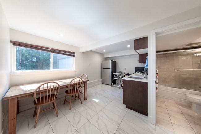 Kitchen with freestanding refrigerator, light countertops, recessed lighting, light marble finish floors, and a sink | Image 35