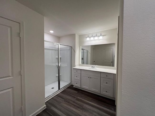 Full bathroom featuring a shower stall, vanity, wood finished floors, a textured wall, and recessed lighting | Image 17