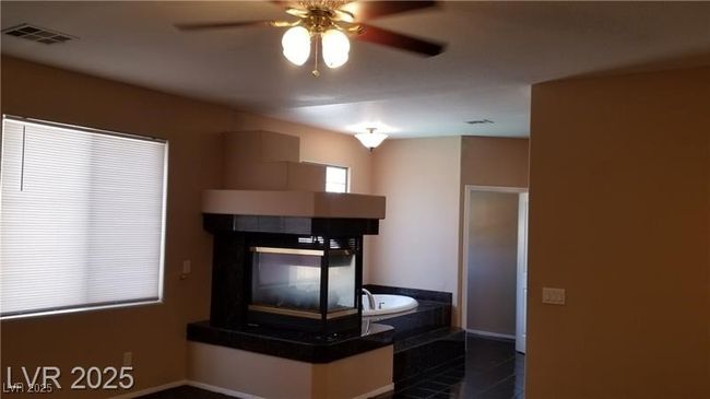 Primary bedroom bathroom with a fireplace, a ceiling fan, and dark countertops | Image 21