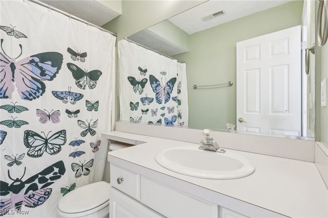 Bathroom featuring curtained shower, visible vents, toilet, and vanity | Image 15