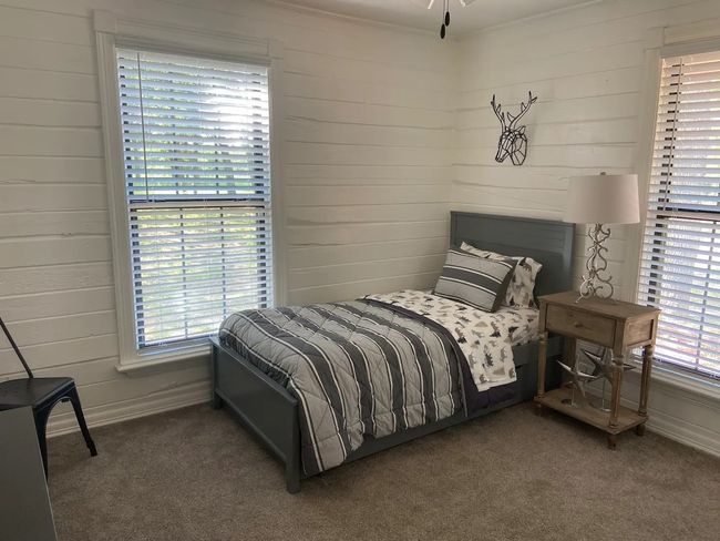 Carpeted bedroom with multiple windows and wood walls | Image 17