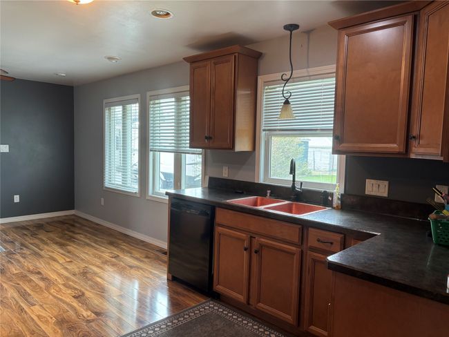 Kitchen featuring black dishwasher, dark countertops, a sink, light wood-style flooring, and recessed lighting | Image 9