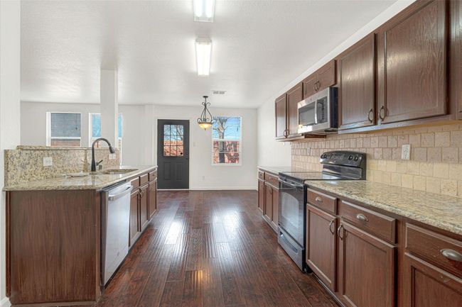 Kitchen featuring black electric range, dishwasher, a sink, stainless steel microwave, and dark wood finished floors | Image 16
