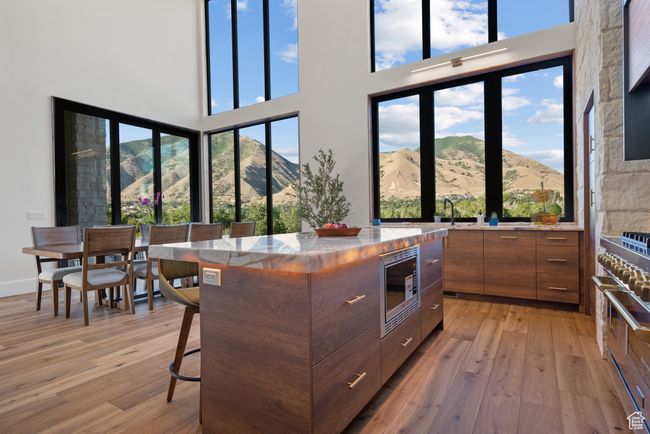 Kitchen with appliances with stainless steel finishes, modern cabinets, light wood-style floors, brown cabinetry, and a high ceiling | Image 35