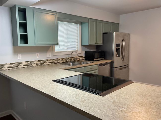 Kitchen featuring appliances with stainless steel finishes, decorative backsplash, and light countertops | Image 4