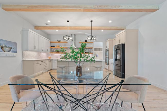 Dining room with beam ceiling, light wood finished floors, recessed lighting, and a chandelier | Image 11