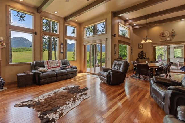 Living area with a chandelier, beamed ceiling, a high ceiling, hardwood / wood-style floors, and a mountain view | Image 19
