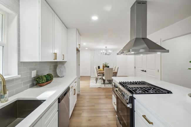 Kitchen with appliances with stainless steel finishes, island exhaust hood, a sink, white cabinets, and light wood-style floors | Image 11