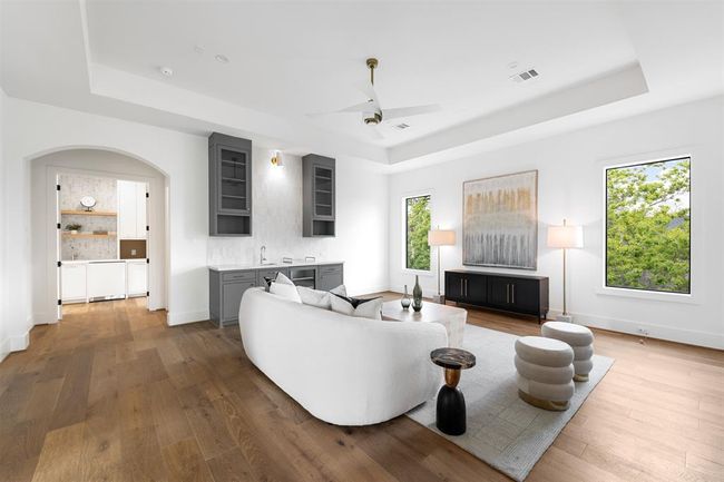ace upstairs is designed for both comfort and style, featuring a sleek wet bar with custom cabinetry for easy entertaining. Large windows flood the room with natural light, while hand-selected fan white oak flooring adds a warm, timeless touch to the space. | Image 34