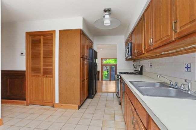 Kitchen featuring black appliances, a sink, light countertops, decorative backsplash, and brown cabinets | Image 7