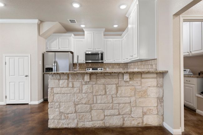 Kitchen featuring stainless steel appliances, light stone counters, backsplash, white cabinetry, and recessed lighting | Image 8