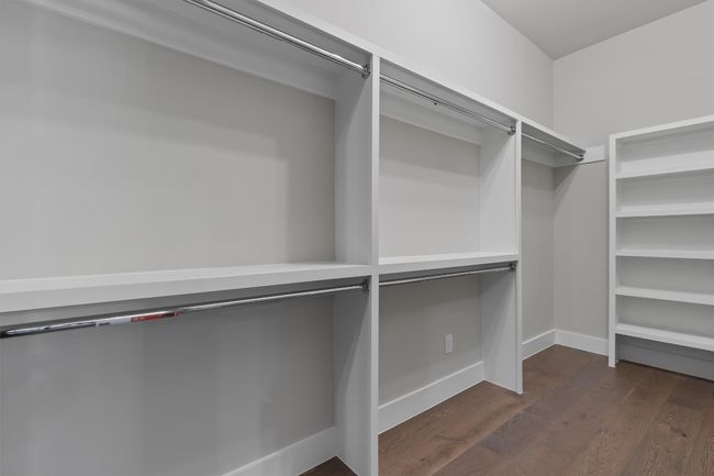 Walk in primary closet with dark wood finished floors | Image 22