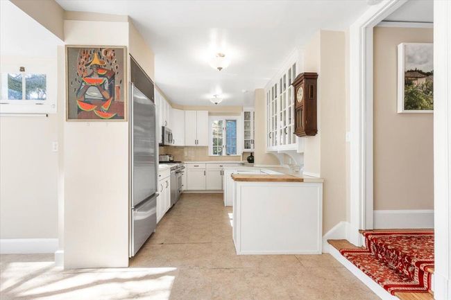 Kitchen with tasteful backsplash, appliances with stainless steel finishes, glass insert cabinets, light countertops, and white cabinetry | Image 12