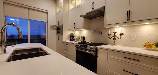 Kitchen with under cabinet range hood, stainless steel appliances, a sink, and light countertops | Image 16