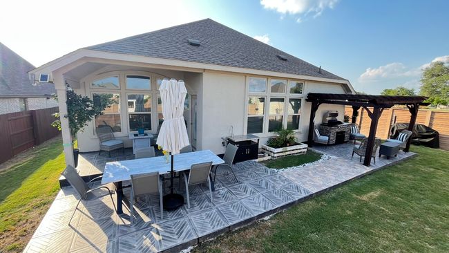 Rear view of house with a pergola, stucco siding, a patio area, a shingled roof, and outdoor dining space | Image 32