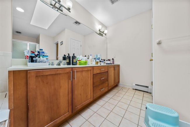 Bathroom featuring visible vents, a baseboard radiator, double vanity, and tile patterned flooring | Image 26