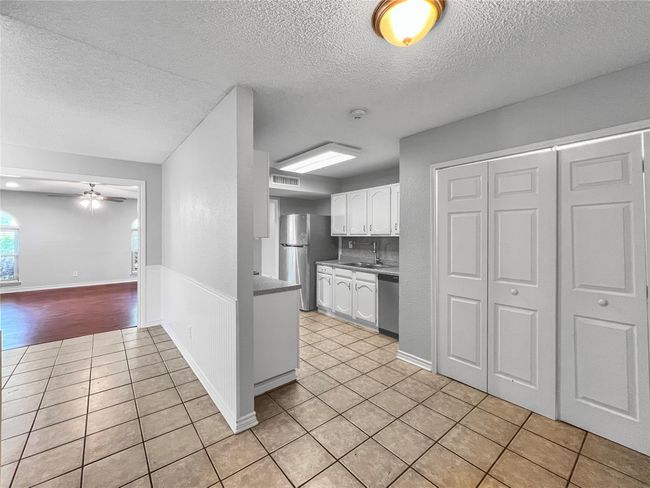 Kitchen featuring appliances with stainless steel finishes, light tile patterned floors, a textured ceiling, white cabinetry, and a ceiling fan | Image 4
