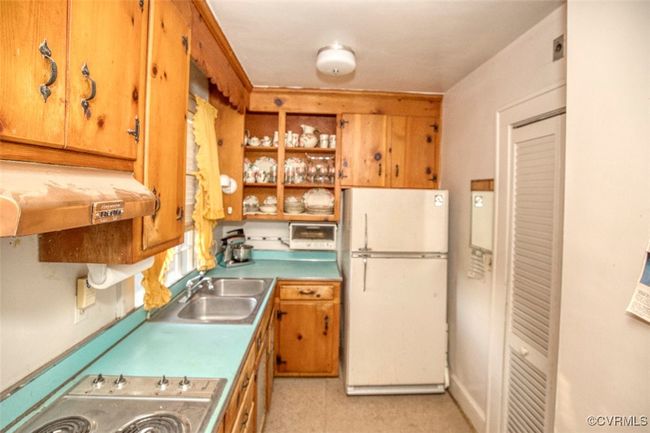 Kitchen with under cabinet range hood, a sink, stainless steel stovetop, and freestanding refrigerator | Image 24
