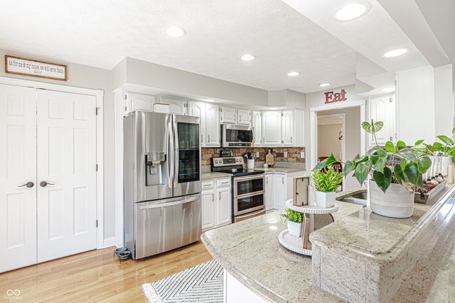 kitchen with white cabinets, tasteful backsplash, appliances with stainless steel finishes, and light wood-type flooring | Image 9