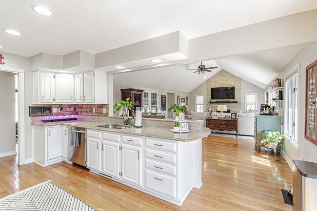 kitchen with dishwasher, a ceiling fan, a sink, light wood-type flooring, and a peninsula | Image 10