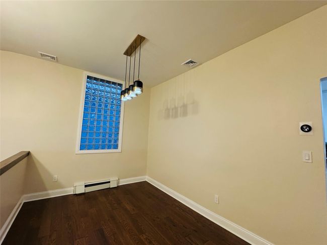 Unfurnished room with a baseboard heating unit and dark wood finished floors | Image 5