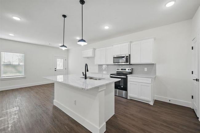 Kitchen featuring a sink, stainless steel appliances, dark wood-type flooring, and decorative backsplash | Image 9
