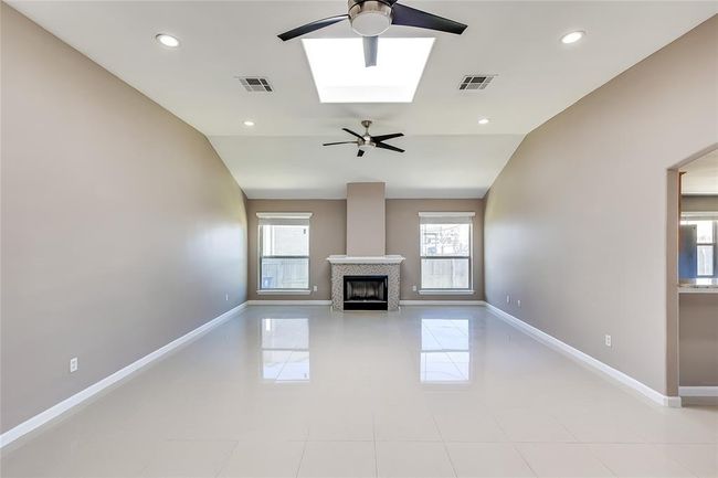 Unfurnished living room featuring ceiling fan, healthy amount of natural light, vaulted ceiling, a fireplace, and recessed lighting | Image 6