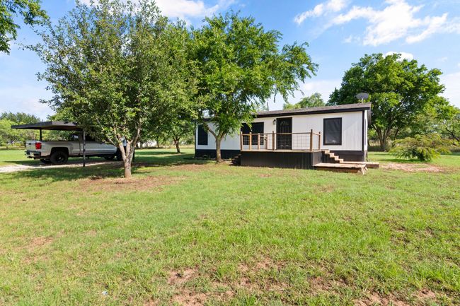 View of green lawn featuring a carport and a deck | Image 6